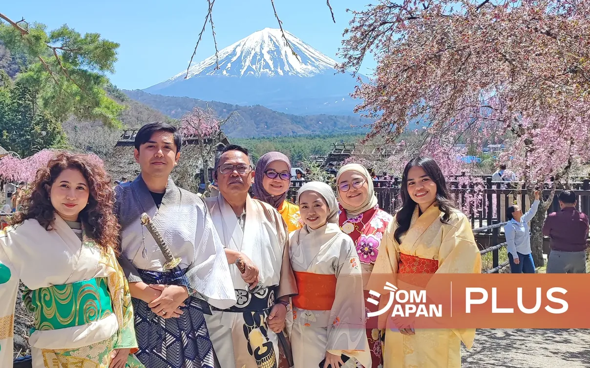 A JomJapan Plus group in kimono under cherry blossom, with Mount Fuji behind